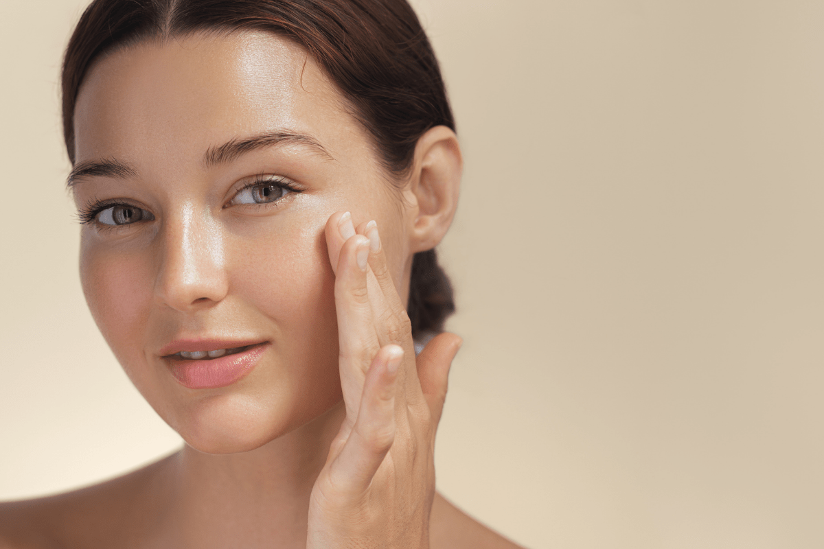 Close-up of a woman touching her face to showcase healthy, glowing hydrated skin after a professional facial treatment.
