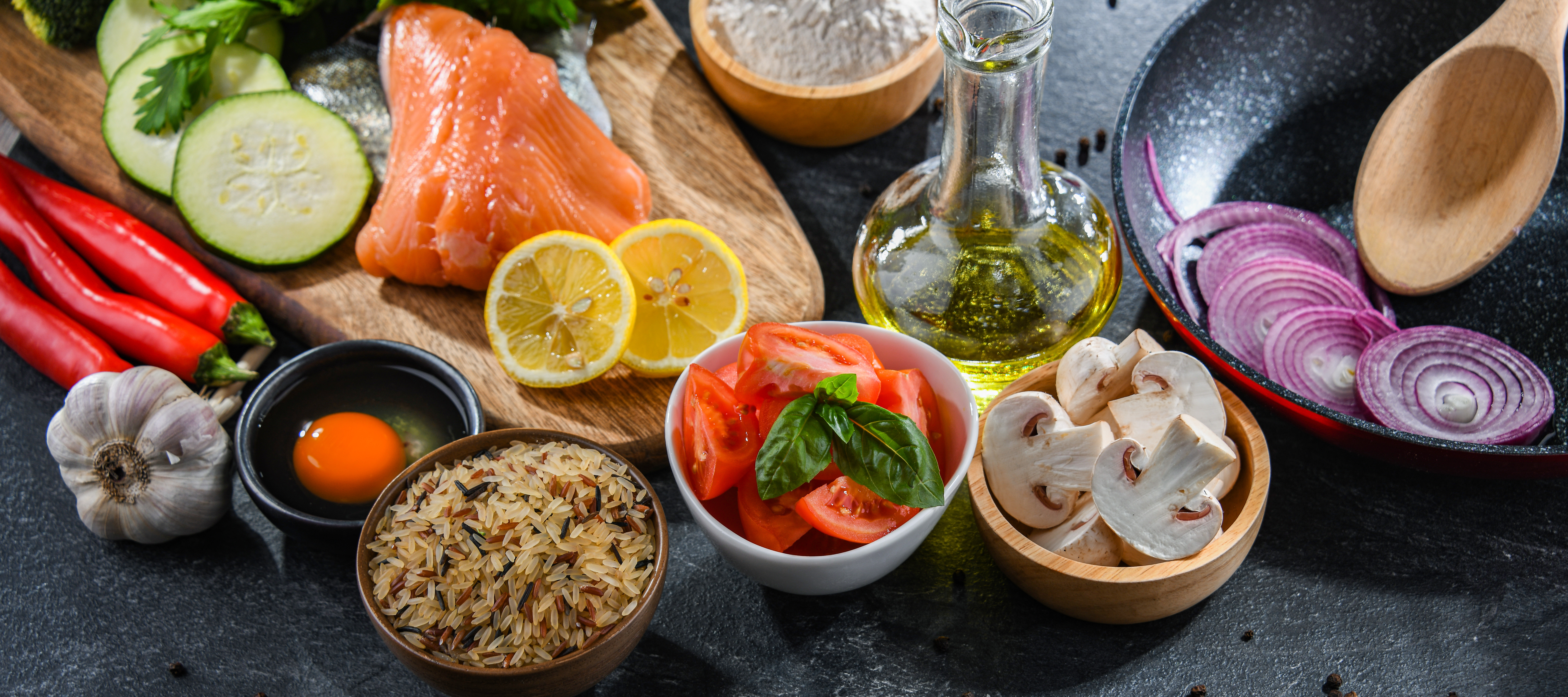 Fresh vegetables, herbs and pantry ingredients laid out on a kitchen table