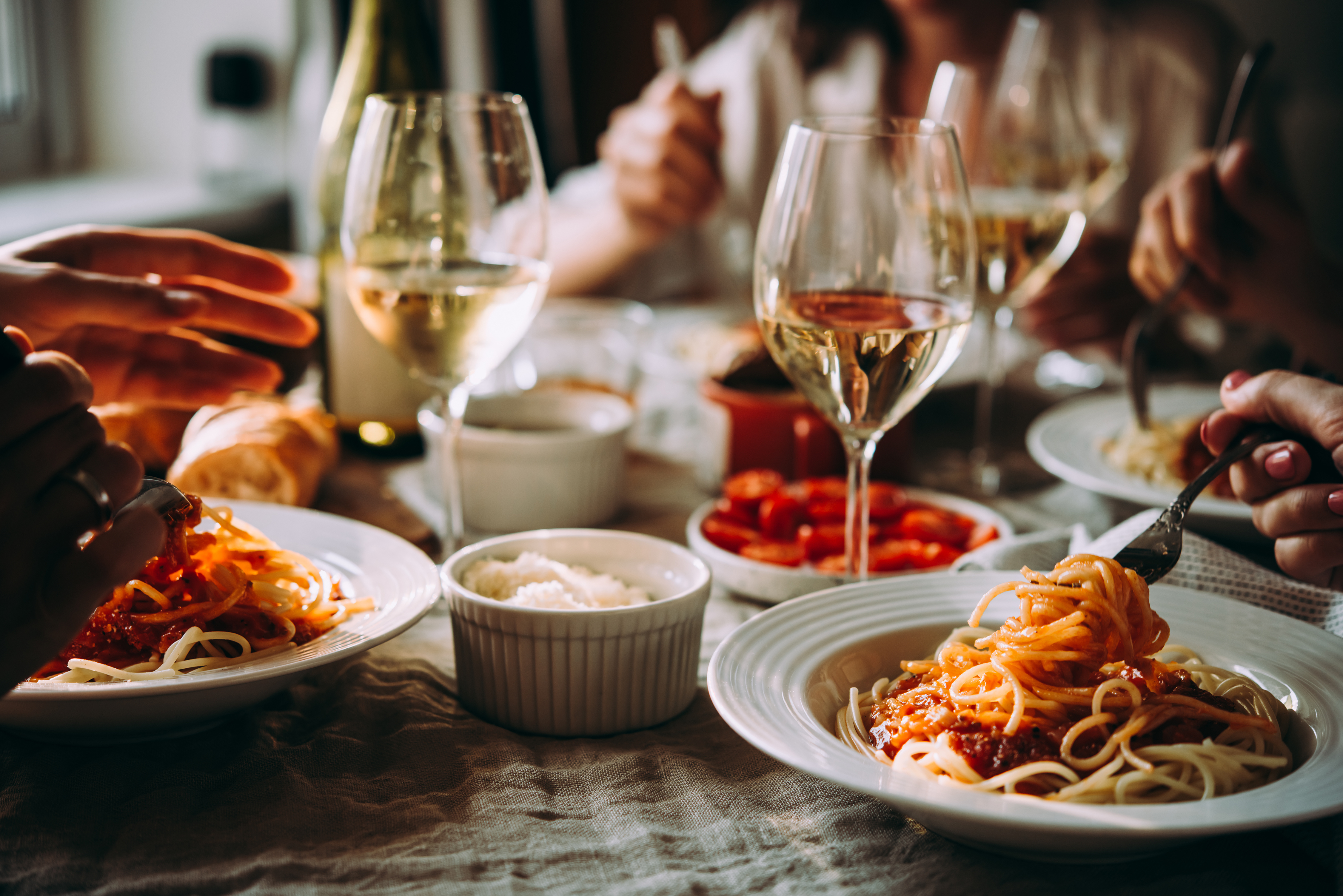 A laid table with pasta and wine glasses set for guests