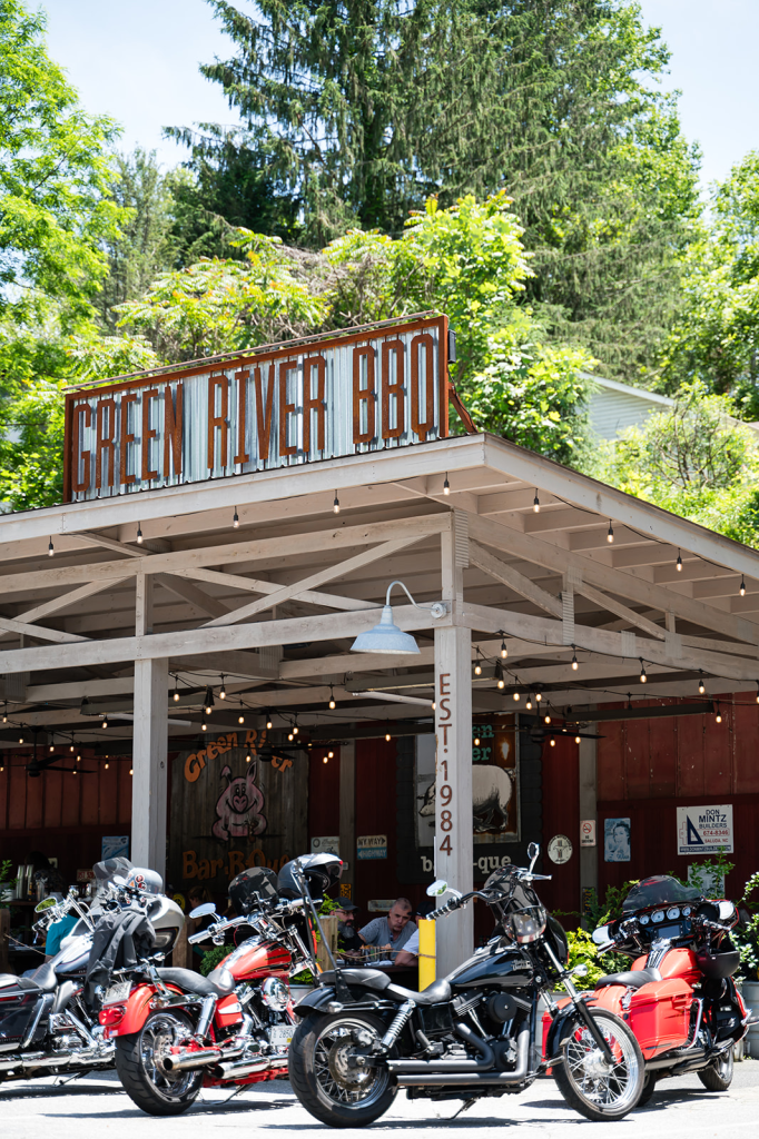 'green river bbq' sign on a rustic open-air eatery with string lights and motorcycles parked in front.