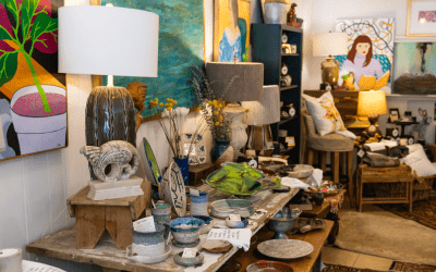 Colorful showroom of vintage and handmade home decor, with lamps, pottery, and artwork displayed on tables and shelves.