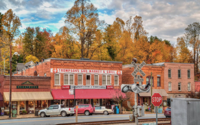 Autumnal main street with brick storefronts, colorful fall trees, and parked cars in front of thompson's old market & grill.