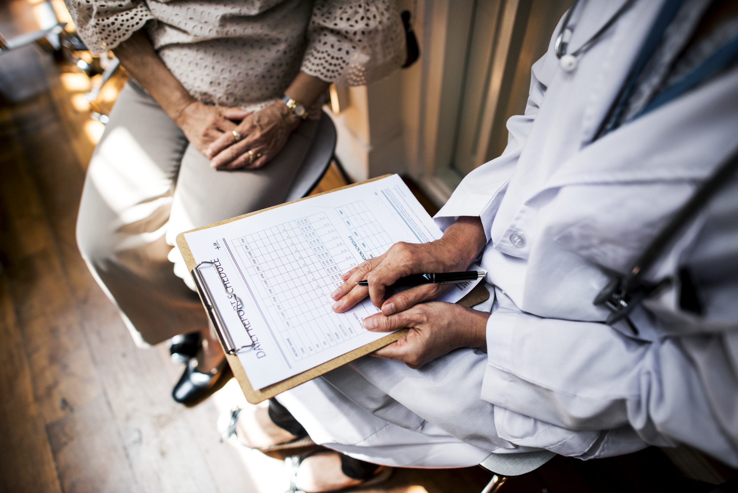 A doctor looks over a form with a patient. We see their hands.