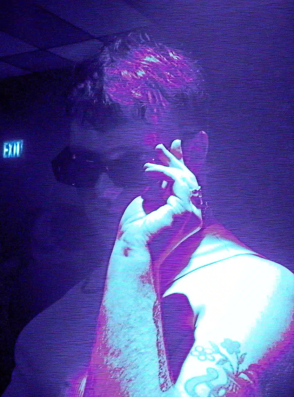 A stylized image of Sam in a club with their sunglasses on.