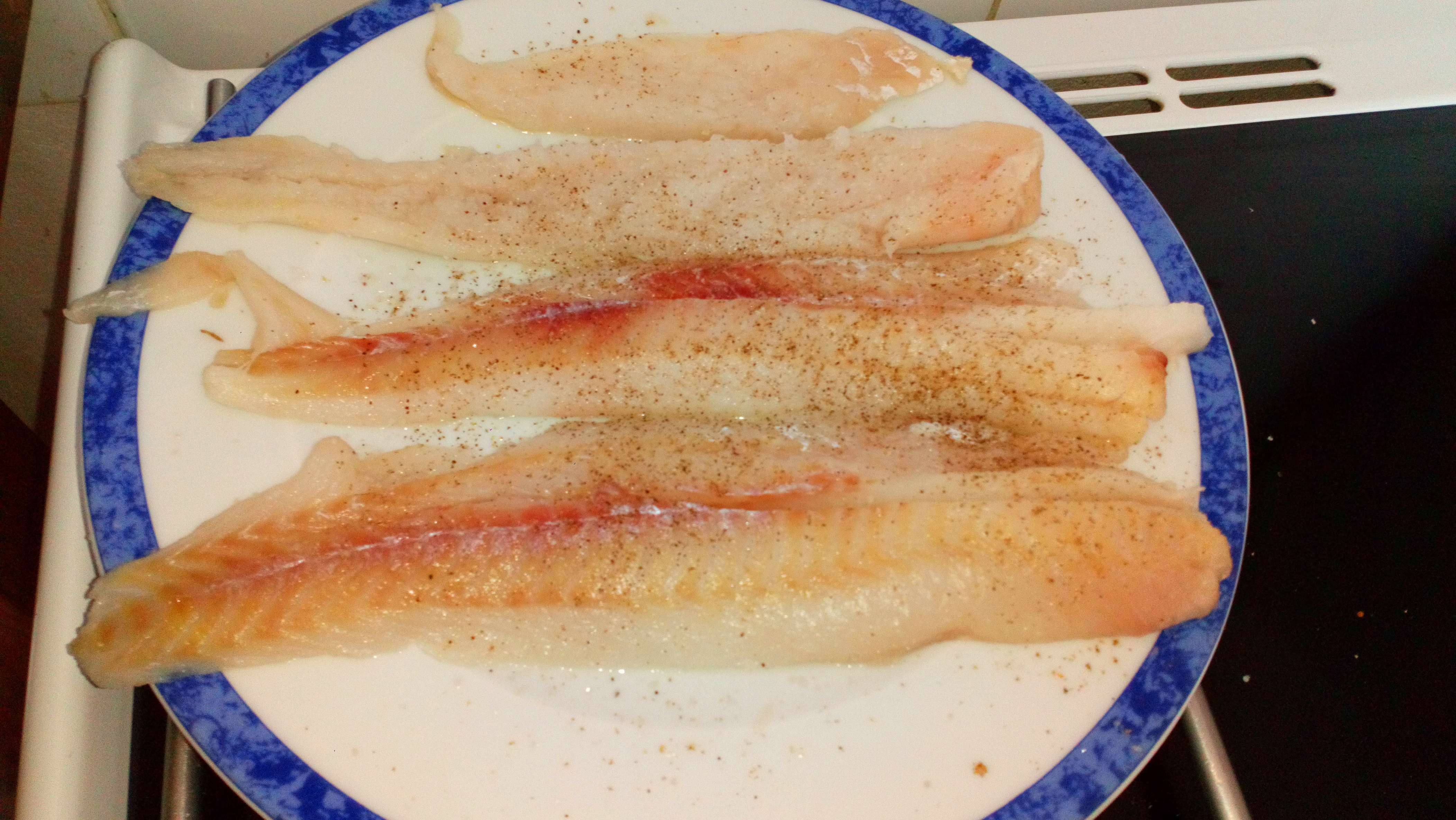 Saler et poivrer les petits filets de poisson, type colin. Salt and pepper the small filet of fish.