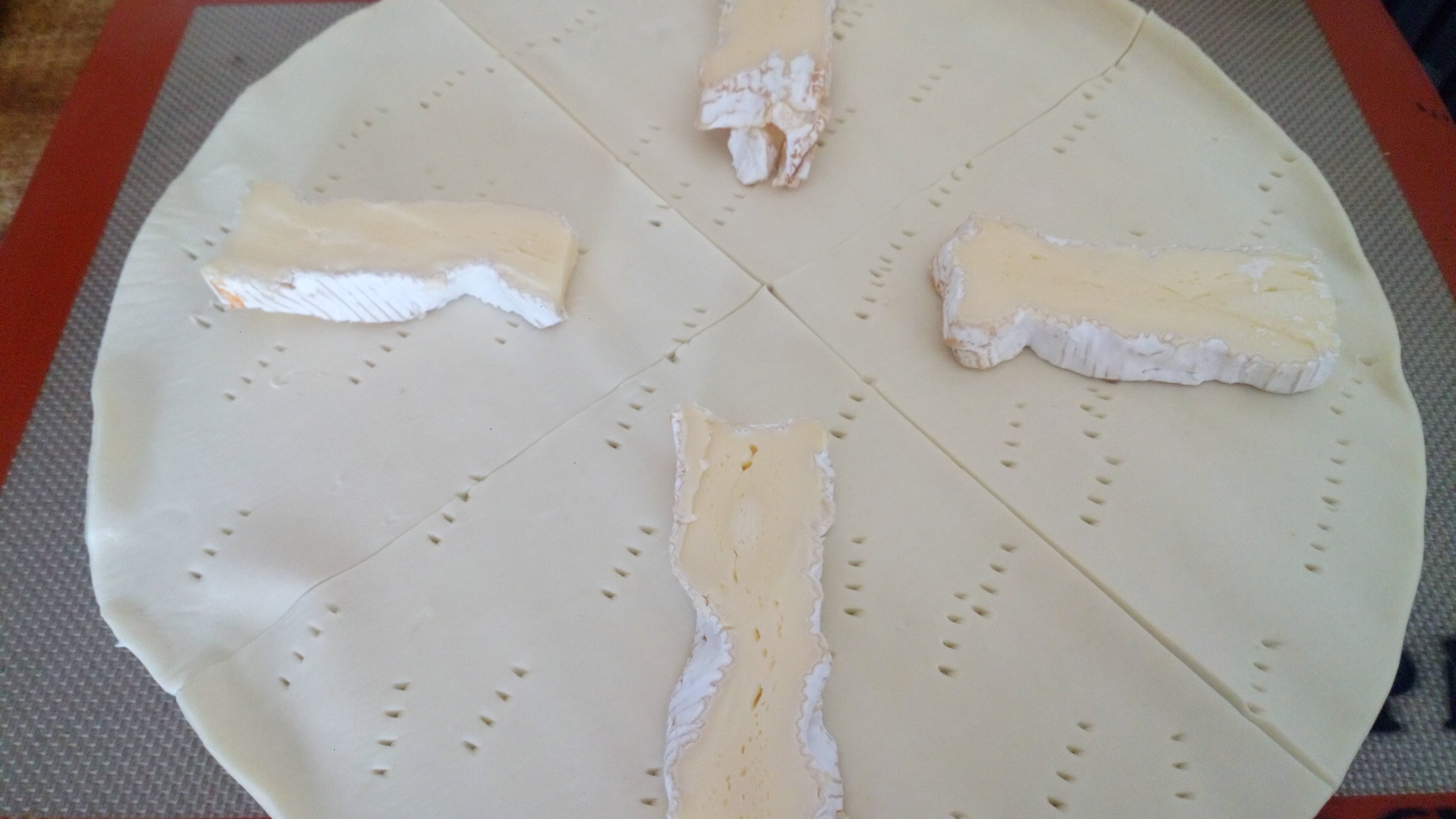 Dérouler le rouleau de pâte feuilletée, la piquer, démarquer en 4 parts et mettre les tranches de camembert. Unwind the roller of puff paste, prick it, mark down in 4 parts and put the slices of camembert cheese.