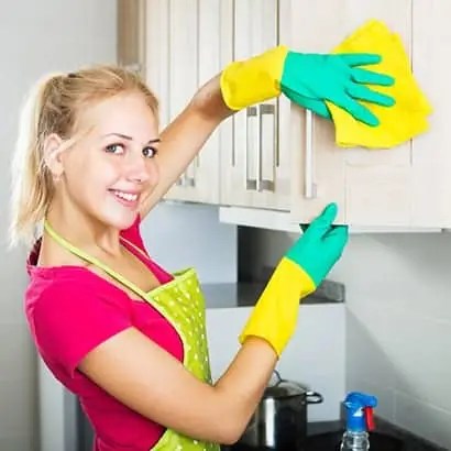 Radiant Residences team member deep cleaning and wiping down a wall with a smile — trusted residential cleaning in San Diego.