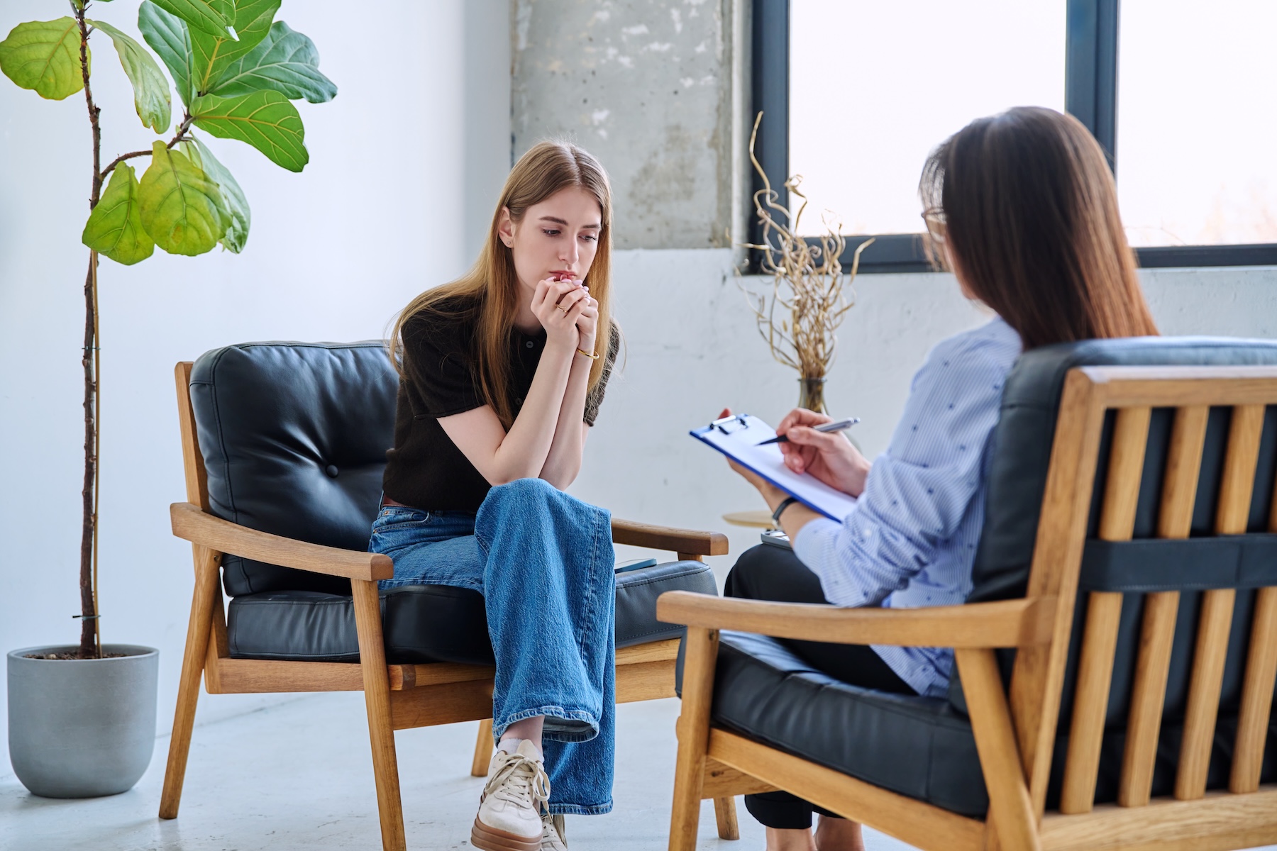 young woman sits in a chair talking to therapist about progress in her fentanyl detox program
