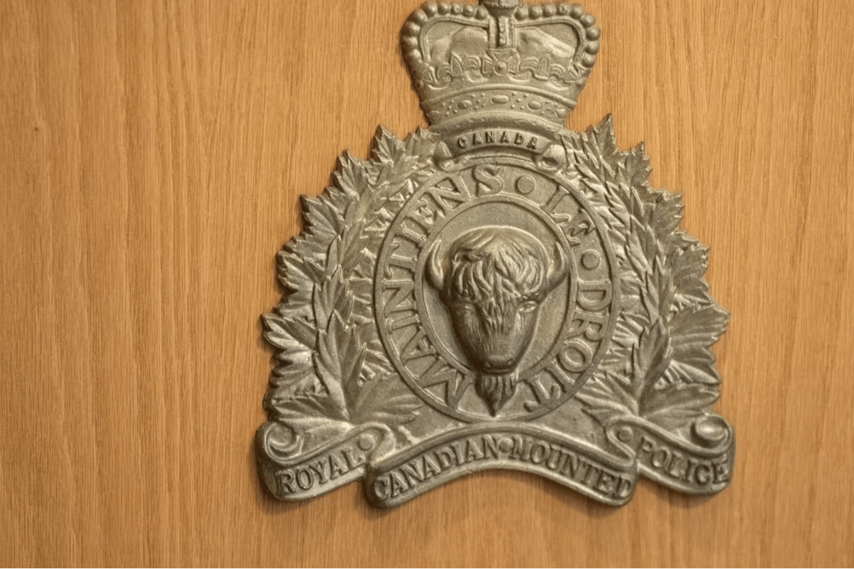 RCMP Royal Canadian Mounted Police badge with a beaver emblem, bordered by maple leaves, mounted on a wooden surface.”,