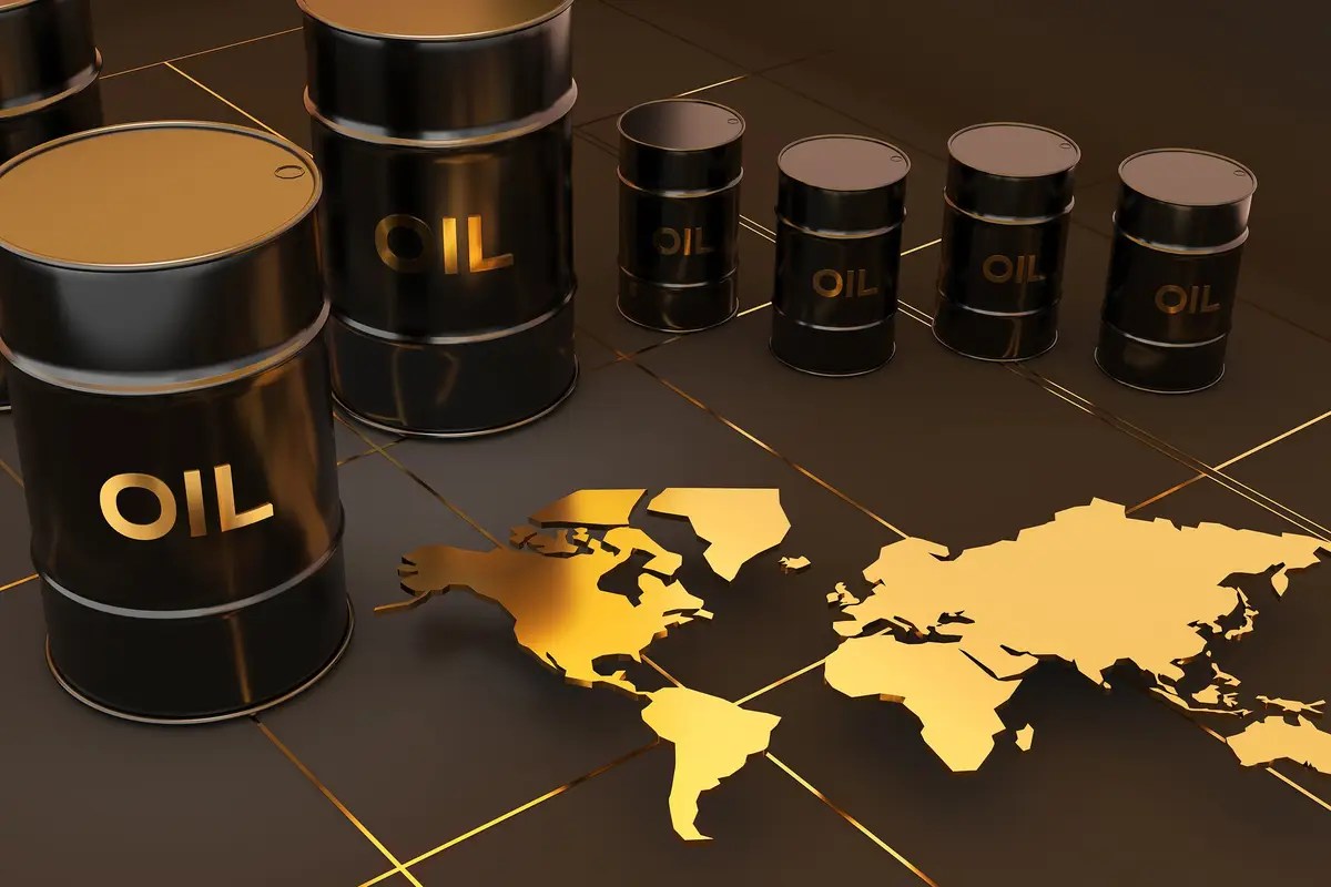Oil barrels labeled OIL on a dark industrial floor with a gold world map motif beneath them, suggesting global oil markets.