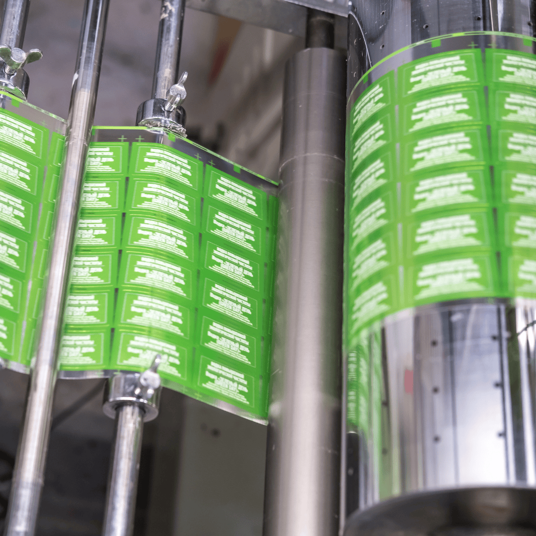 A close-up of a label printing machine producing green labels in sheets.