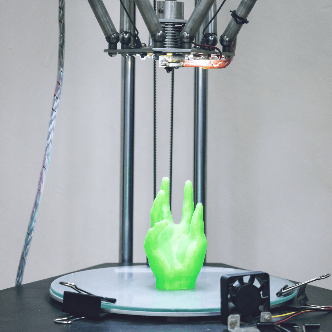 A 3D printer is creating a green model of a hand on its build platform.
