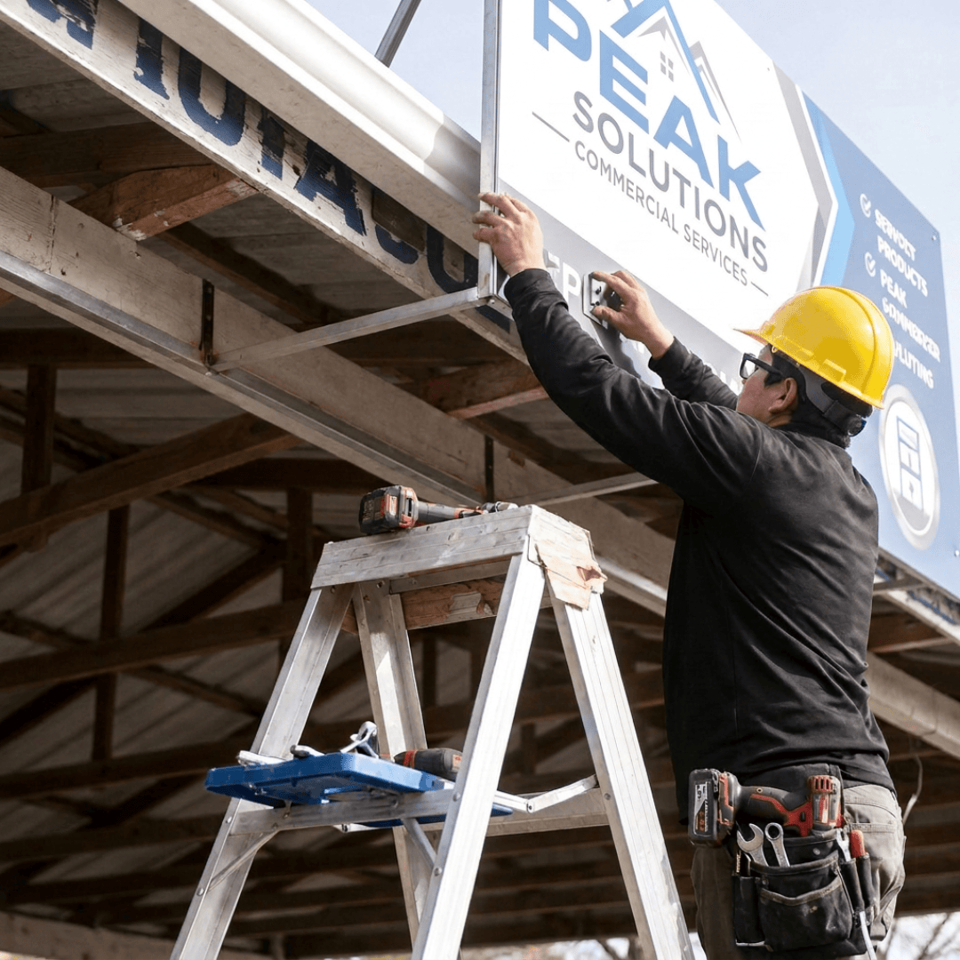 A man is crafting a sign for Peak Solutions.