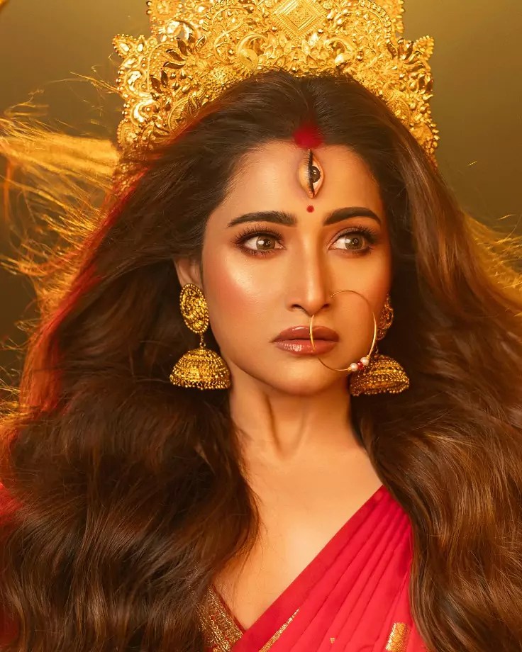 Sudiptaa Banerjee holding a trident in a Navratri-themed photoshoot, dressed in red and adorned with golden accessories.