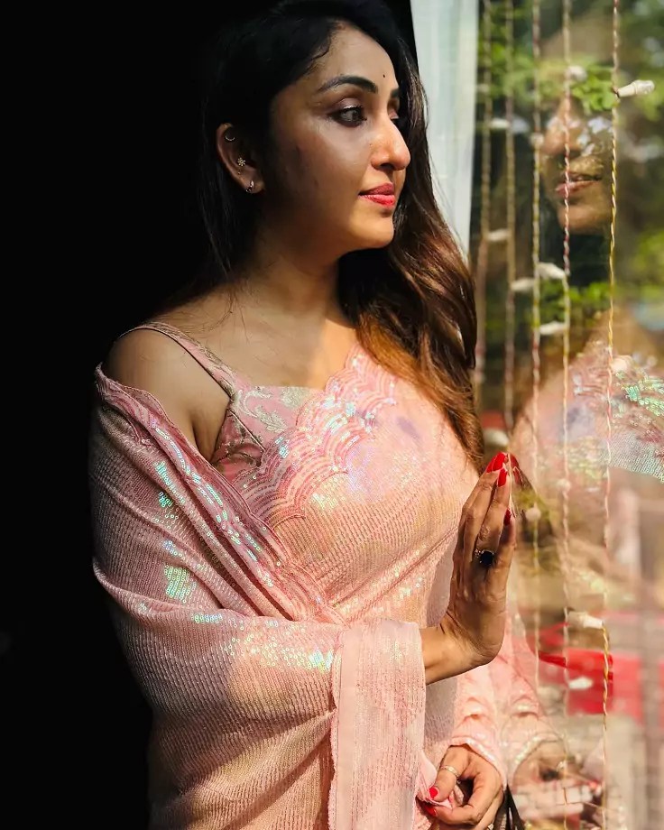 Elegant Nithya Das in a shimmering saree with soft waves and minimal makeup.