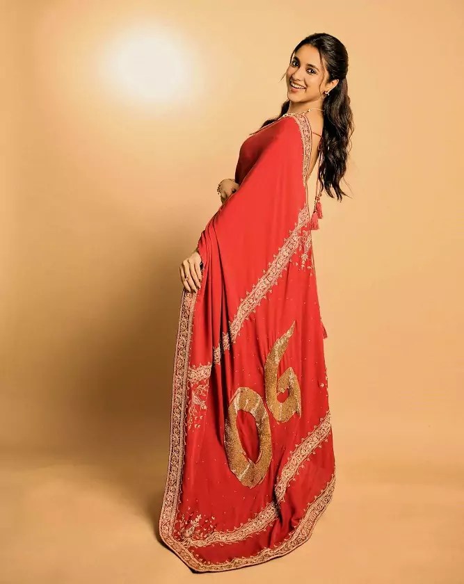 Priyanka Mohan seated in her red saree during the OG event, smiling with poise.