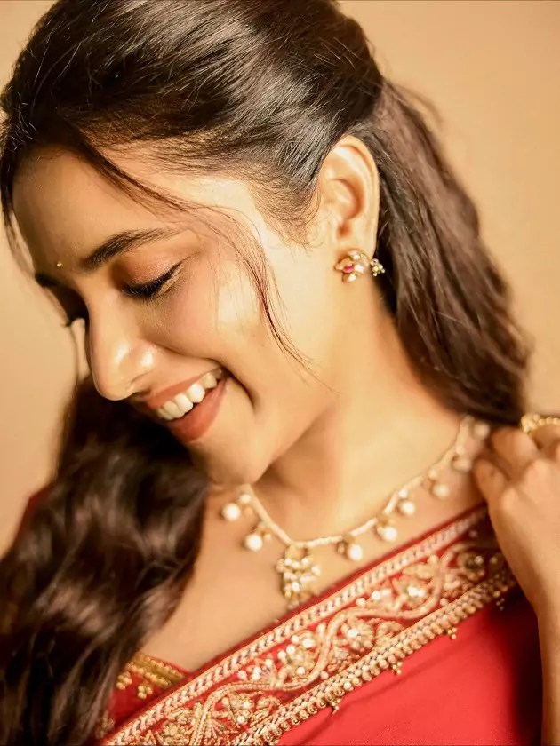 Priyanka Mohan in a red saree with golden embroidery at the OG event, posing gracefully.