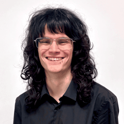 Portrait of Sam Fairclough, smiling, with dark curly hair and glasses.