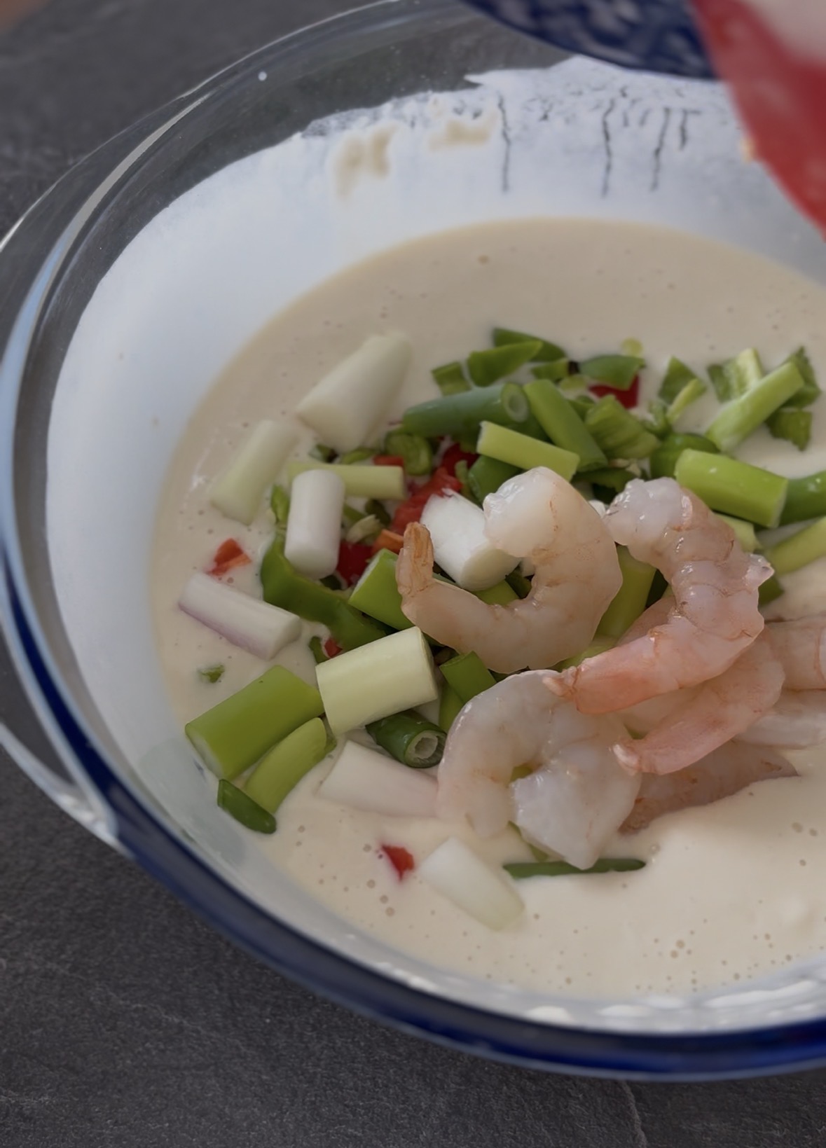 Gamberi e verdure incorporati nella pastella per preparare l'autentico Haemul Pajeon coreano.