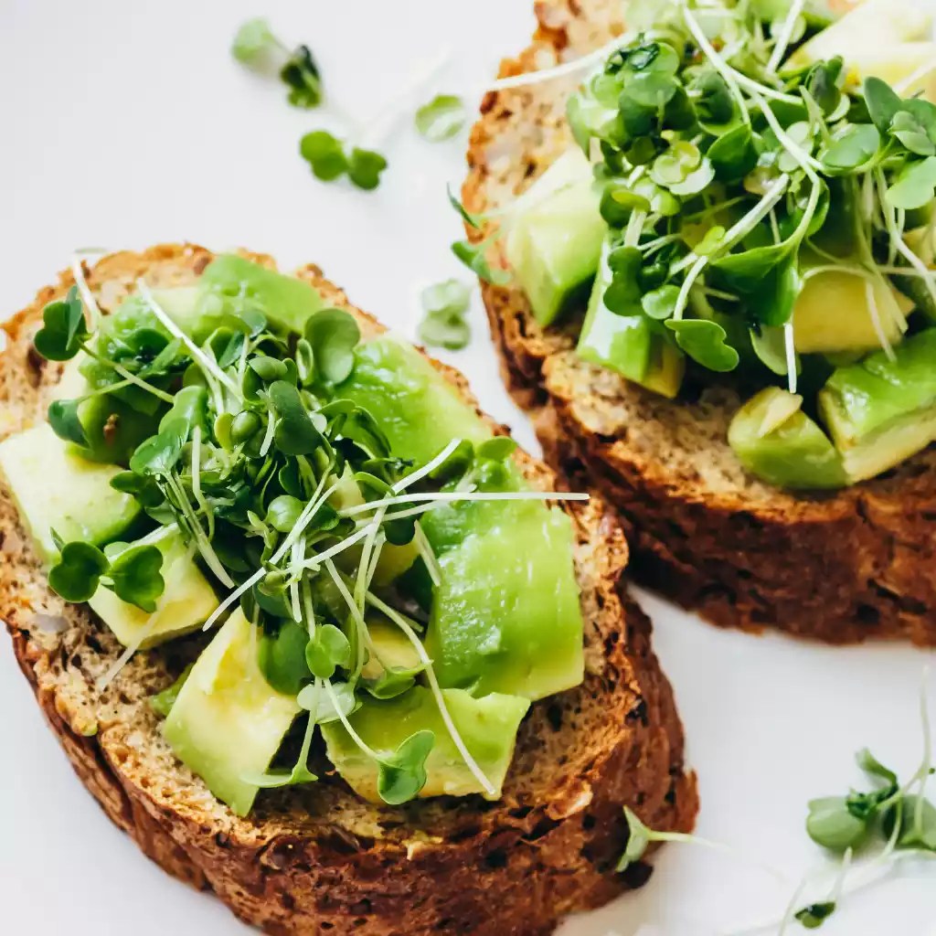 Whole-grain avocado toast topped with fresh microgreens from a microgreen subscription service for a healthy meal option.