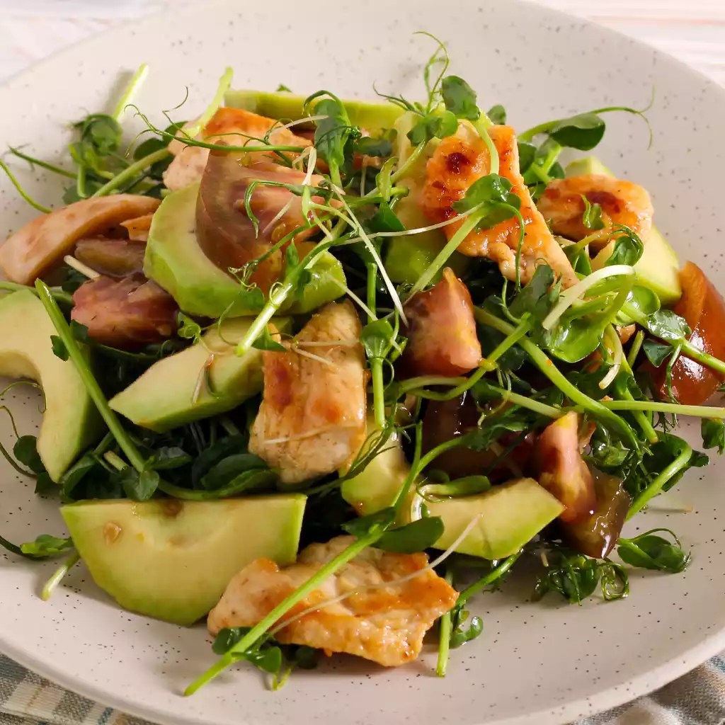 Fresh chicken salad with avocado slices and pea shoot and sunflower microgreens from a microgreen subscription service for a healthy and satisfying meal."