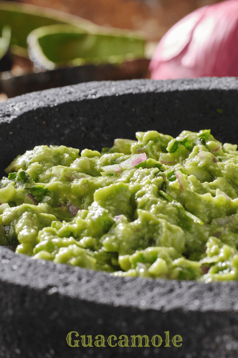 guacamole in a stone grey bowl with red onion in background