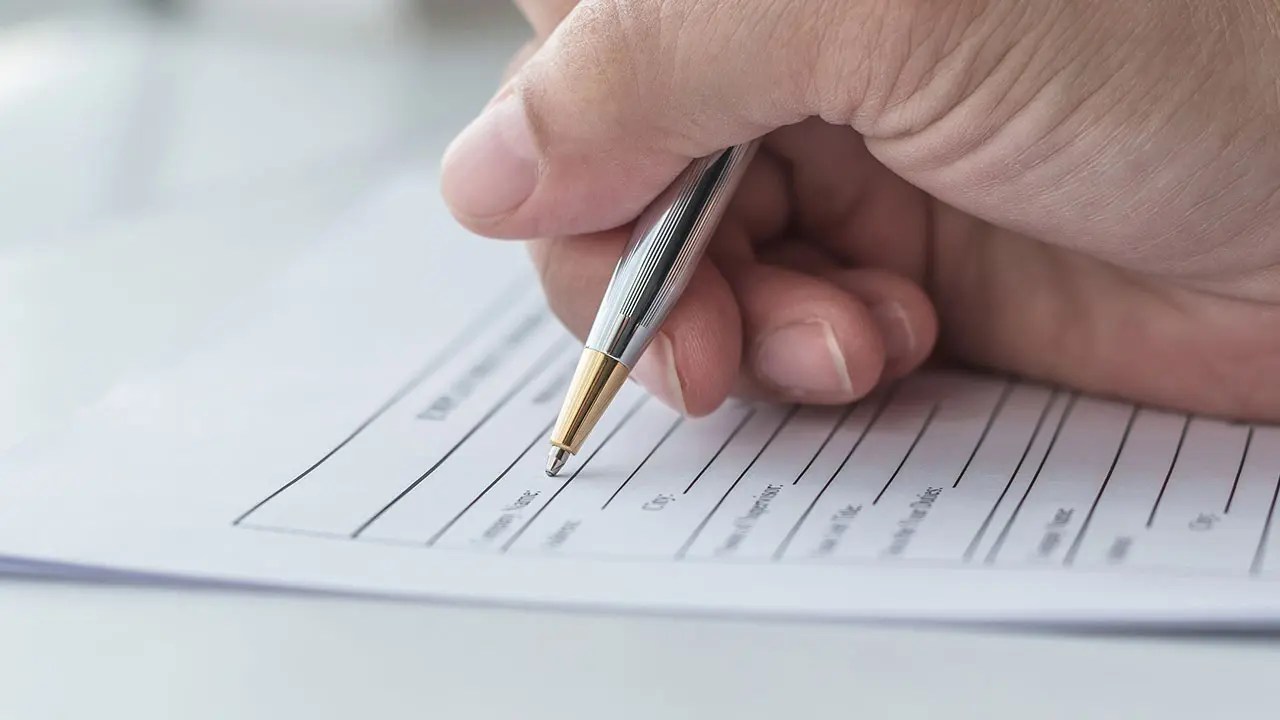 Close-up of an applicant signing the final paperwork for a California BPPE application for institutional licensing.