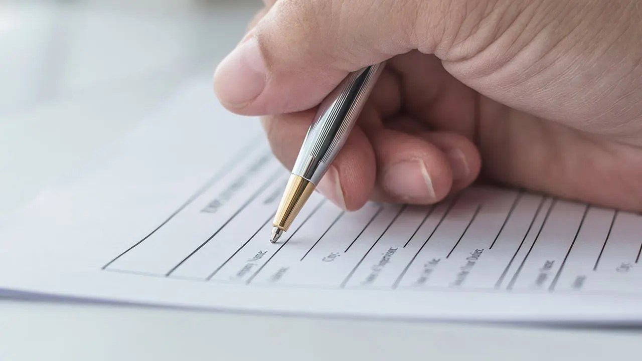 Hand signing a school application form.