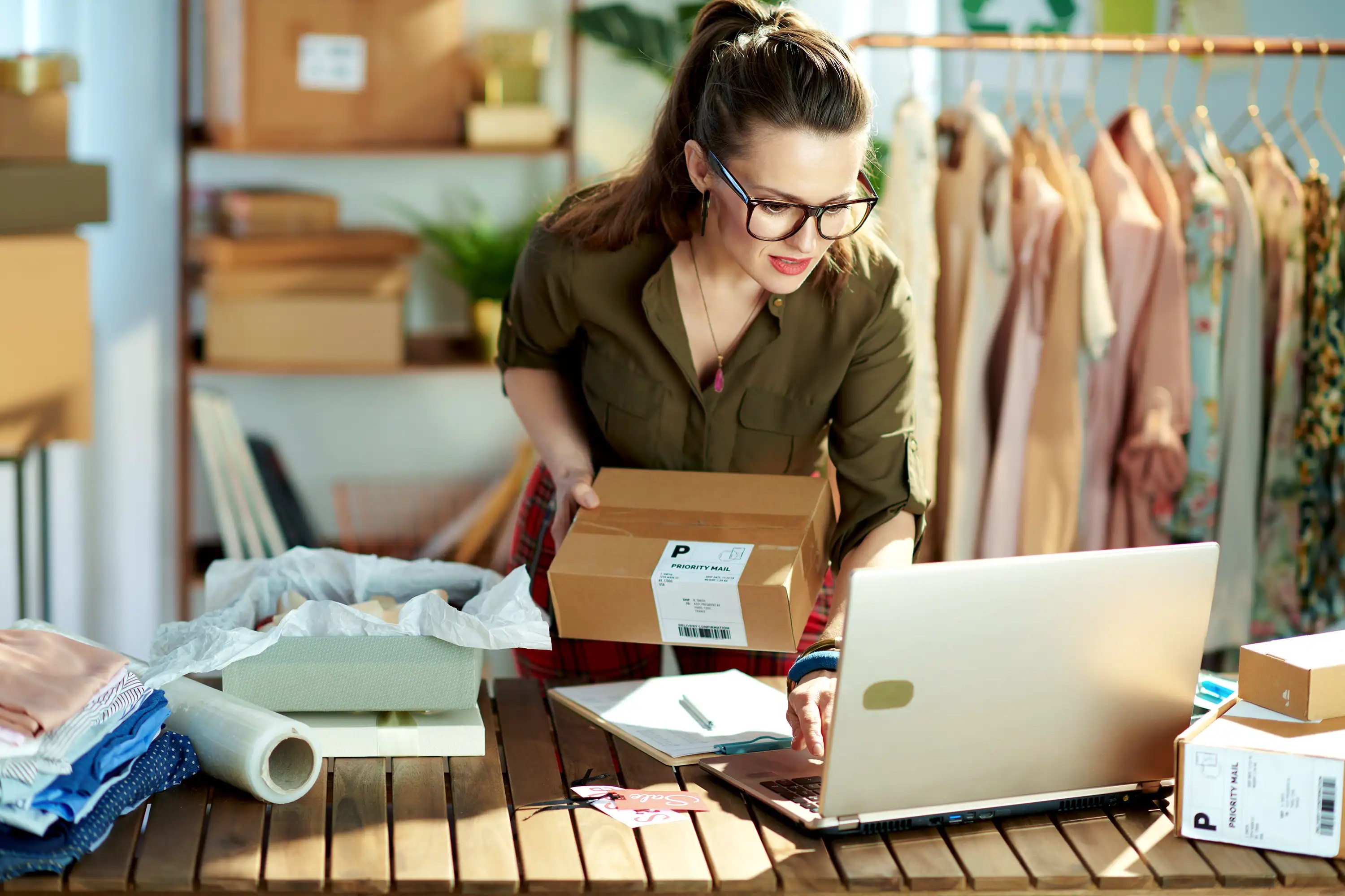 Woman worker preparing a package and checking the laptop