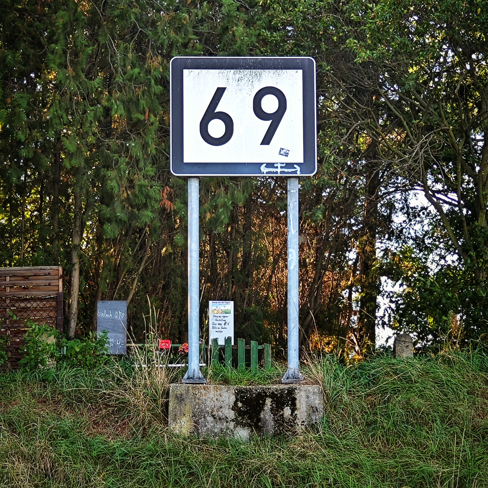 Das Elbkilometerschild 69 steht auf einer Böschung im Grünen.