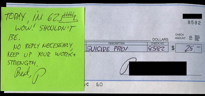 A check with a bright green sticky note containing a supportive message.