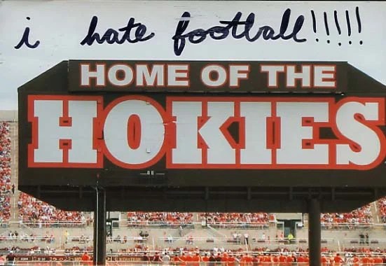 A photo of a sign that reads 'HOME OF THE HOKIES' with a crowd in the background.