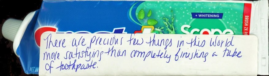 A close-up of a toothpaste tube with handwritten text on a label.