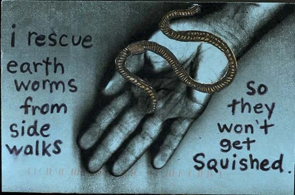 A realistic depiction of a hand holding an earthworm against a dark background.