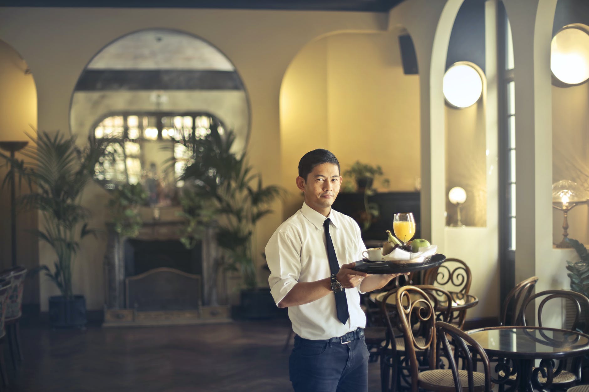 waiter with tray working in stylish restaurant