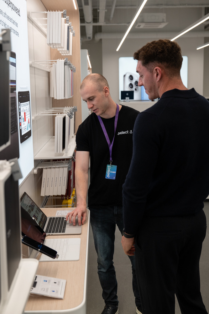 A Select colleague demonstrating a MacBook to a customer