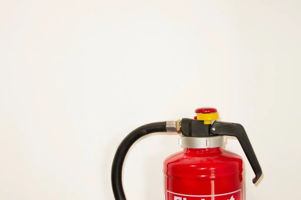 A serviced fire extinguisher mounted against a plain wall