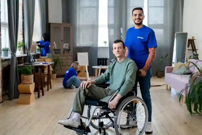 A support worker sitting and talking with a young man who uses a wheelchair