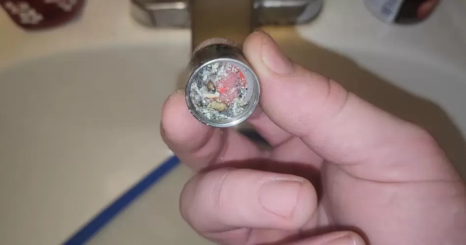 Removed faucet aerator with debris on its screen