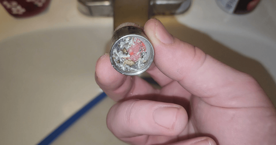Removed faucet aerator with debris on its screen