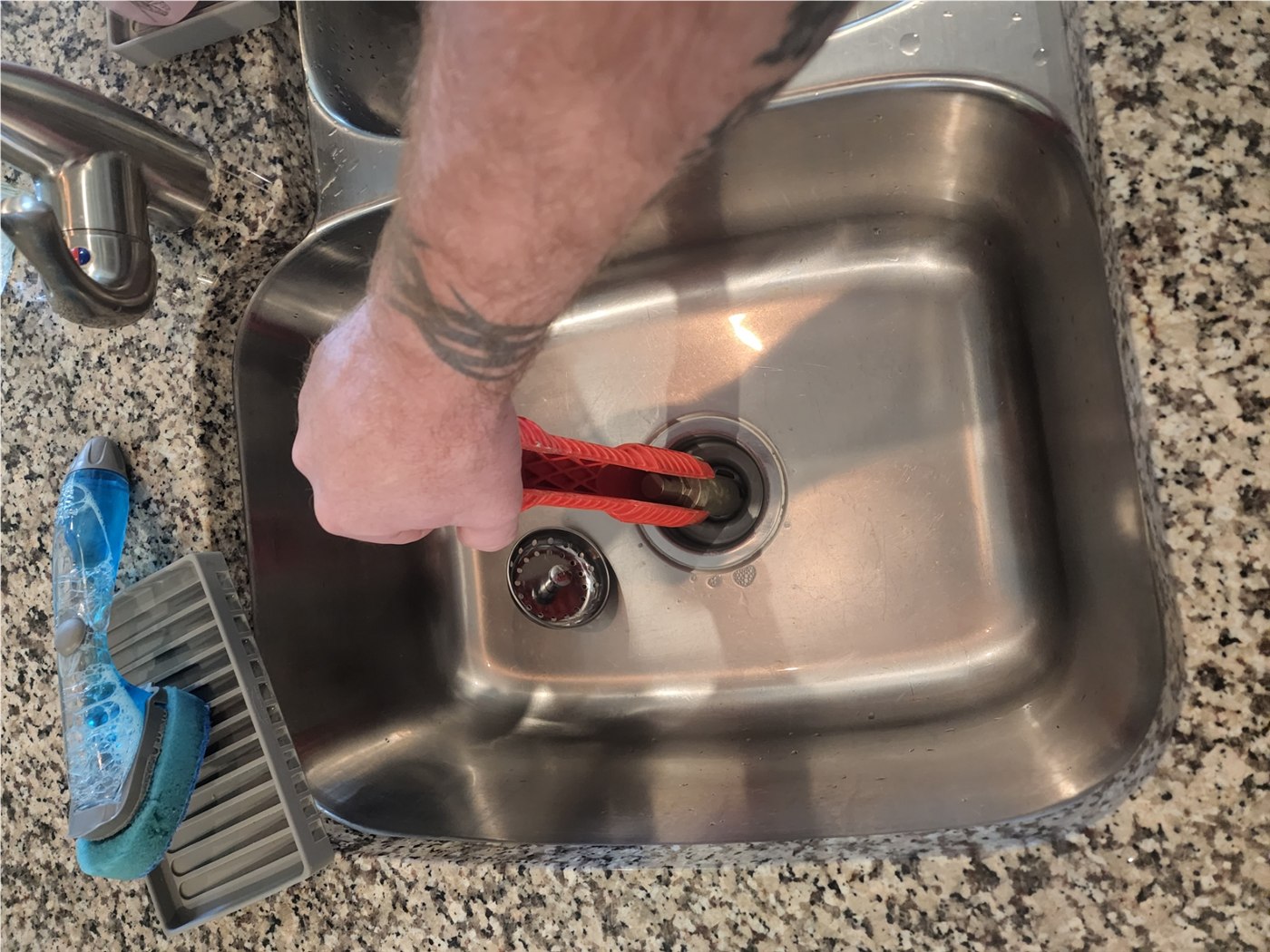 Original job photo of a holding tool engaged in a kitchen sink strainer