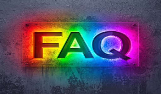Placa de acrílico transparente com efeito gradiente arco-íris vibrante, exibindo as letras "FAQ" em 3D com acabamento metálico e iluminação colorida. As letras apresentam tons que variam de vermelho e amarelo à esquerda, passando por verde no centro, até azul e roxo à direita. A placa possui parafusos decorativos nos cantos e está fixada sobre uma parede texturizada cinza, com reflexos coloridos projetados na superfície abaixo.
