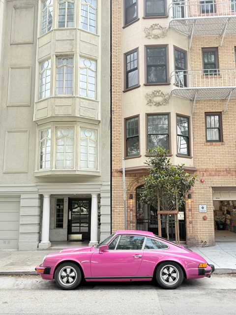 A hot pink Porsche parked on a San Francisco city street