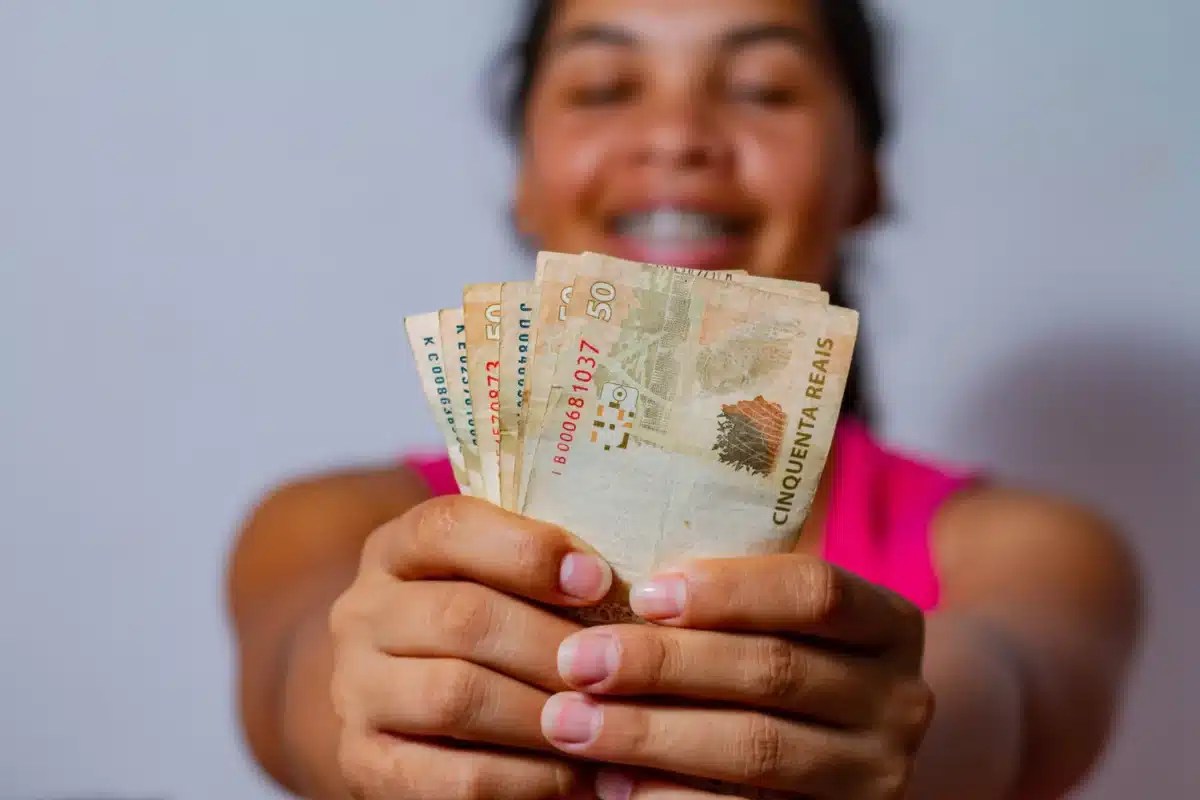 mulher segurando dinheiro para representar o auxílio para mães solteiras