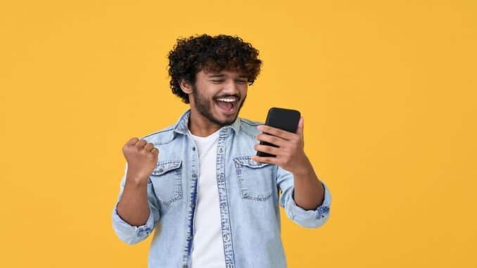 Homem feliz olhando para o celular após quitar dívidas com desconto