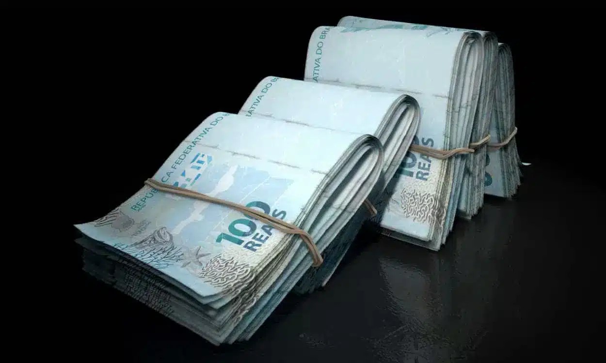 Conjuntos de notas de R$ 100 presas com elástico e apoiadas um nos outros representando R$ 1 milhão