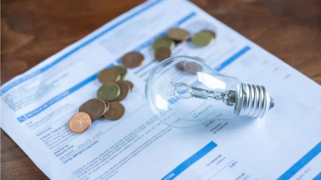 Lâmpada e moedas sobre uma conta de luz.