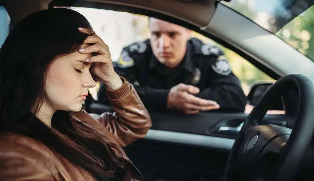 Mulher preocupada dentro de carro. na janela do automóvel, um homem com roupas de guarda fala com ela e aplica multas de trânsito.