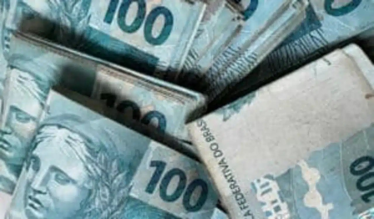 Maço de notas de R$ 100 espalhados em uma superfície representando pagamento