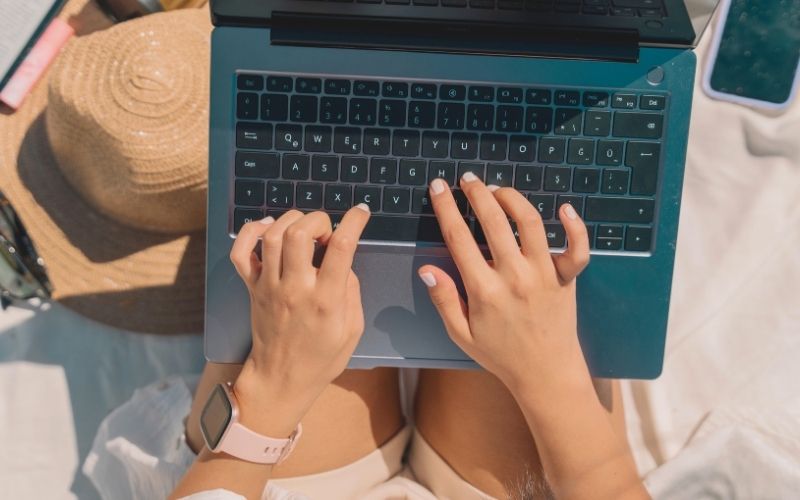 woman typing on a laptop on the beach